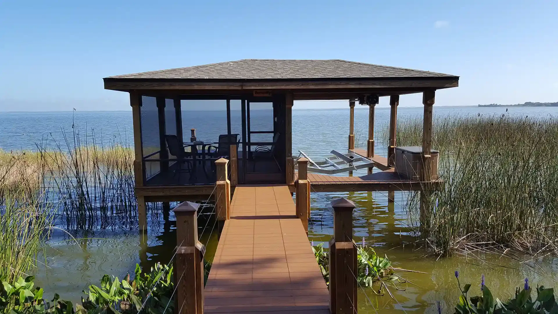 photo of a covered boat dock, aka boat hose, with a screened area