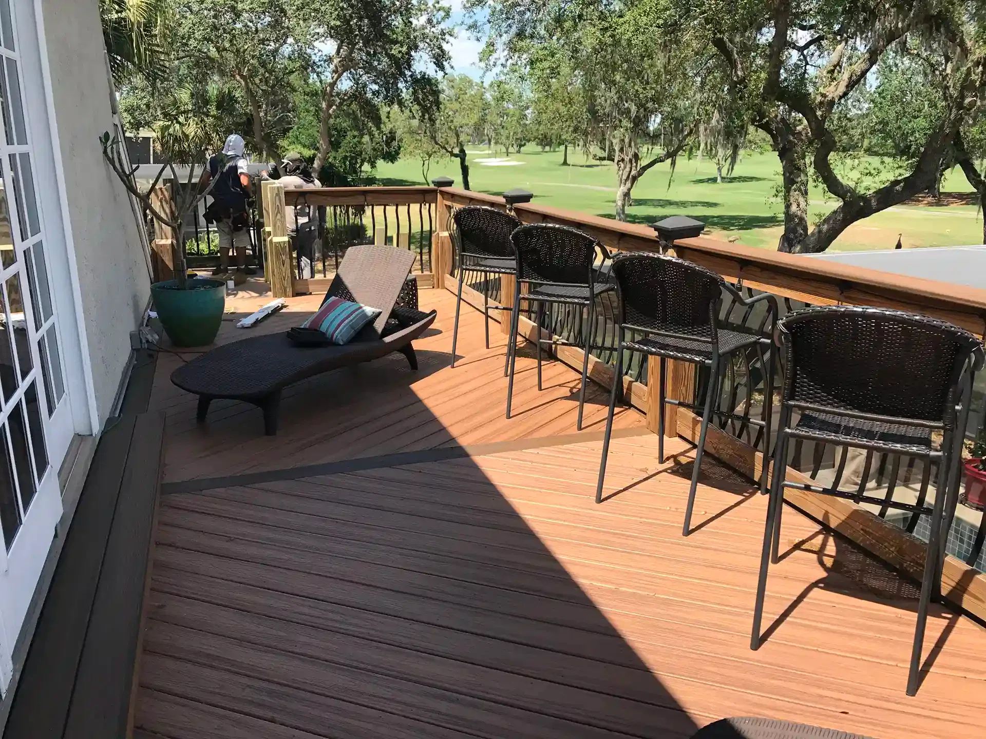 Photo of a deck with a drink rail with bar stools.